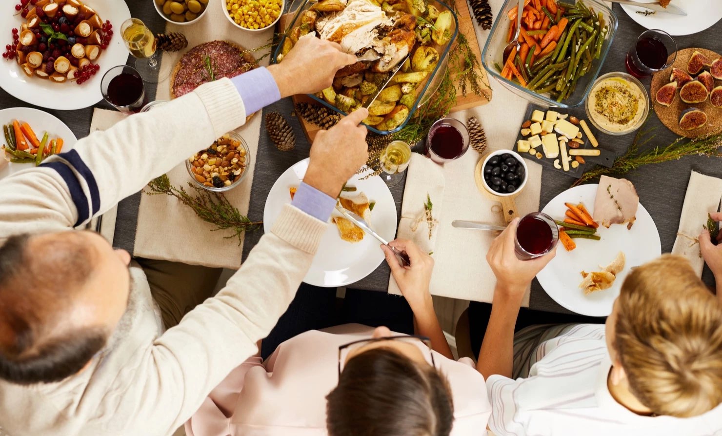 Family gathered around the holiday table passing food.